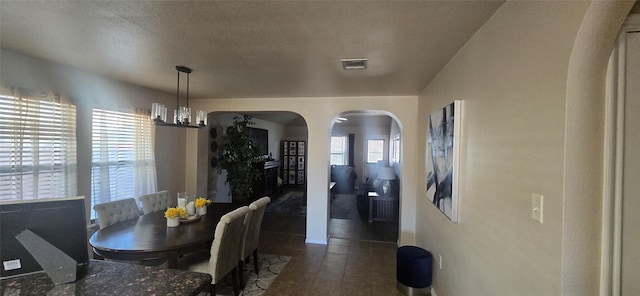 tiled dining area featuring a textured ceiling, a chandelier, and a healthy amount of sunlight