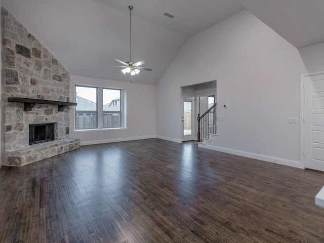 unfurnished living room with a stone fireplace, vaulted ceiling, dark hardwood / wood-style floors, and ceiling fan