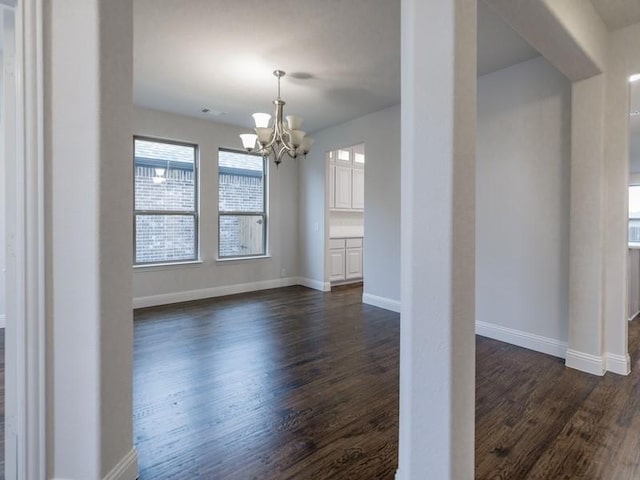 unfurnished dining area featuring dark wood-type flooring and a notable chandelier