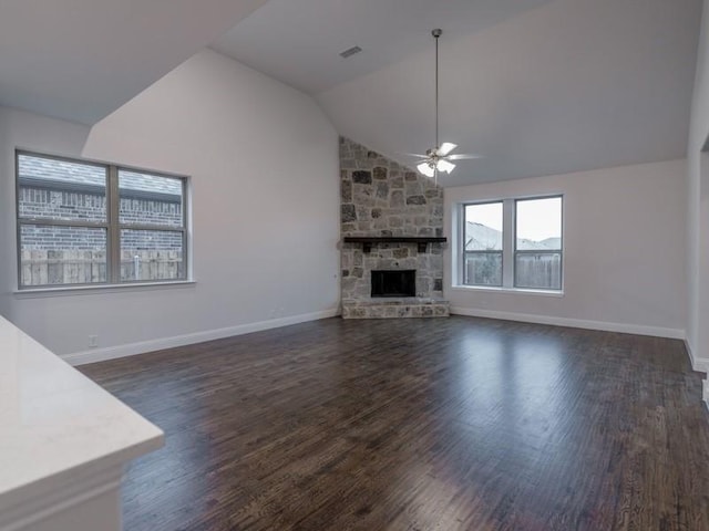 unfurnished living room with ceiling fan, a stone fireplace, dark hardwood / wood-style flooring, and vaulted ceiling