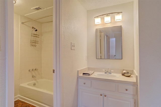 bathroom with vanity, tiled shower / bath combo, and a textured ceiling