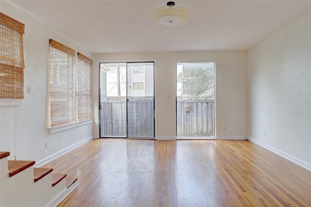 spare room featuring a textured ceiling and light hardwood / wood-style floors