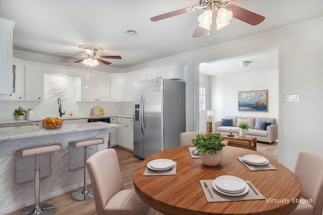 dining room featuring crown molding, a ceiling fan, visible vents, and light wood-type flooring