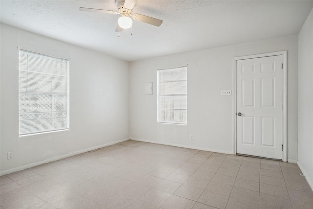 empty room with a healthy amount of sunlight, a textured ceiling, and ceiling fan