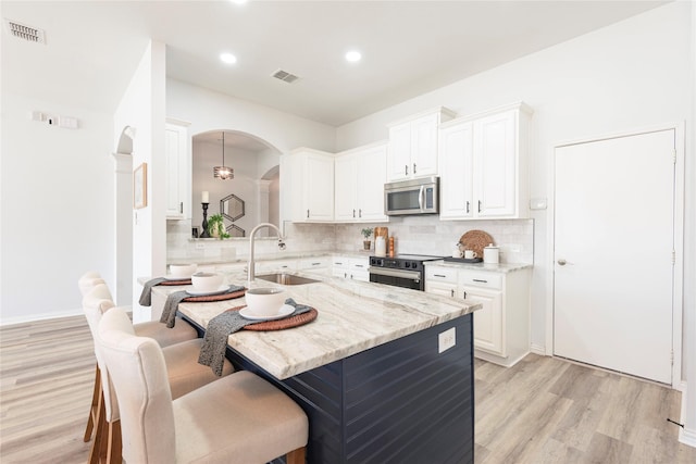 kitchen featuring stainless steel appliances, light stone countertops, sink, and hanging light fixtures