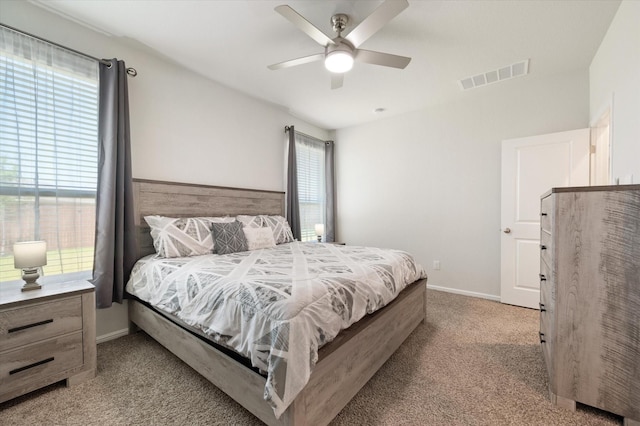 carpeted bedroom featuring multiple windows and ceiling fan