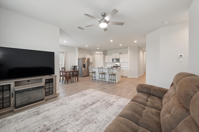 living room with ceiling fan and light wood-type flooring