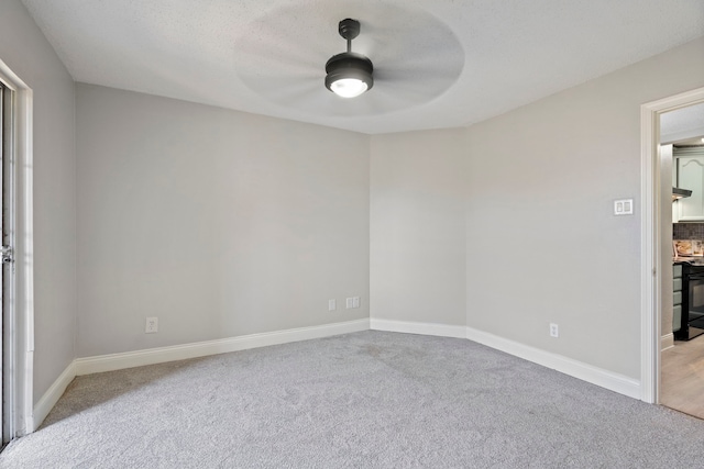 spare room featuring ceiling fan, light colored carpet, and a textured ceiling