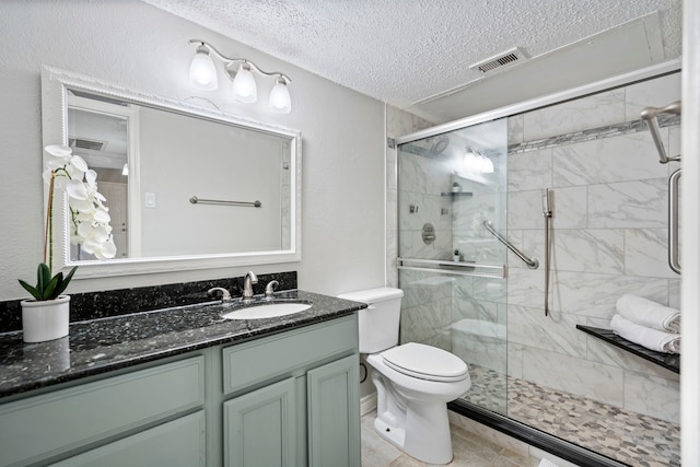 bathroom with tile patterned floors, toilet, a textured ceiling, vanity, and a shower with door