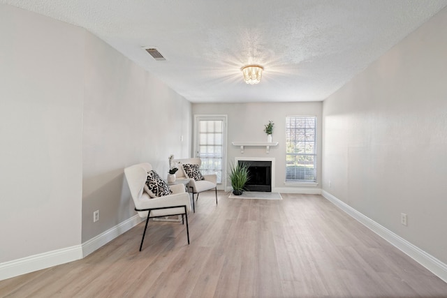 living area featuring a textured ceiling and light hardwood / wood-style floors