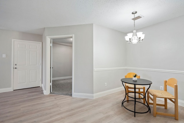 dining area featuring an inviting chandelier, a textured ceiling, and light hardwood / wood-style floors