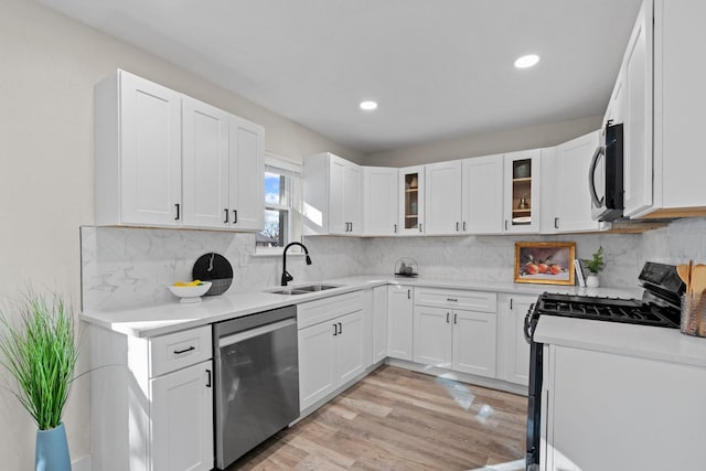 kitchen with sink, black gas range, white cabinetry, backsplash, and stainless steel dishwasher