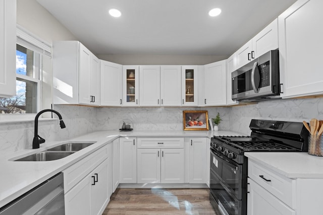 kitchen featuring sink, backsplash, stainless steel appliances, light hardwood / wood-style floors, and white cabinets