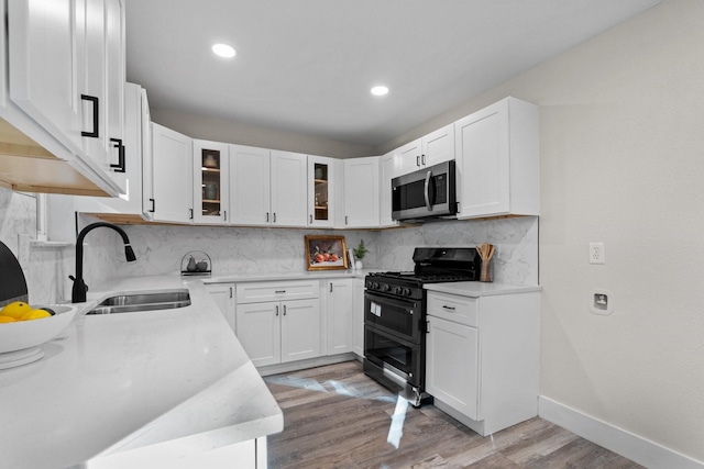 kitchen with sink, light hardwood / wood-style flooring, white cabinetry, decorative backsplash, and range with two ovens