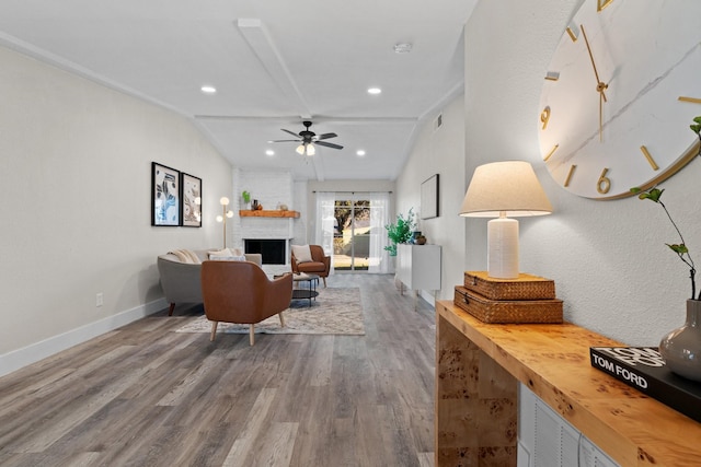 living room with lofted ceiling, hardwood / wood-style flooring, a fireplace, and ceiling fan