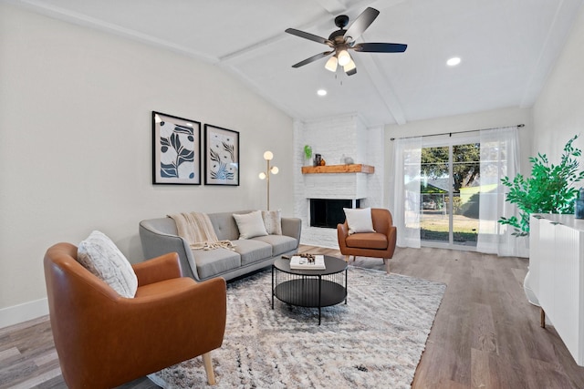 living room with lofted ceiling, wood-type flooring, a large fireplace, and ceiling fan