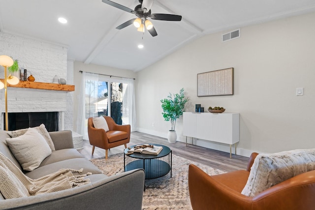 living room featuring ceiling fan, a fireplace, light hardwood / wood-style flooring, and vaulted ceiling with beams