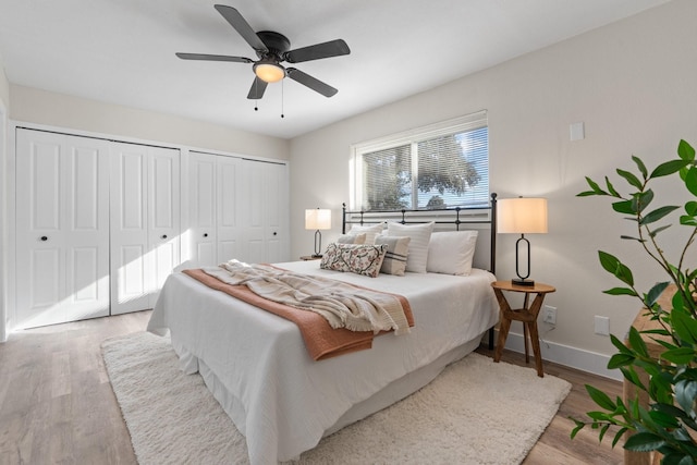 bedroom with two closets, ceiling fan, and light hardwood / wood-style floors