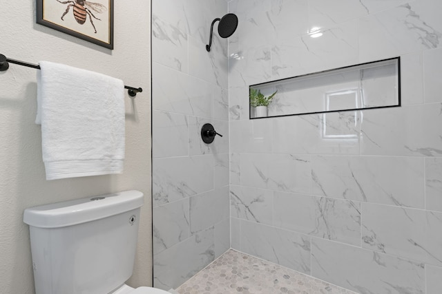 bathroom with toilet and a tile shower