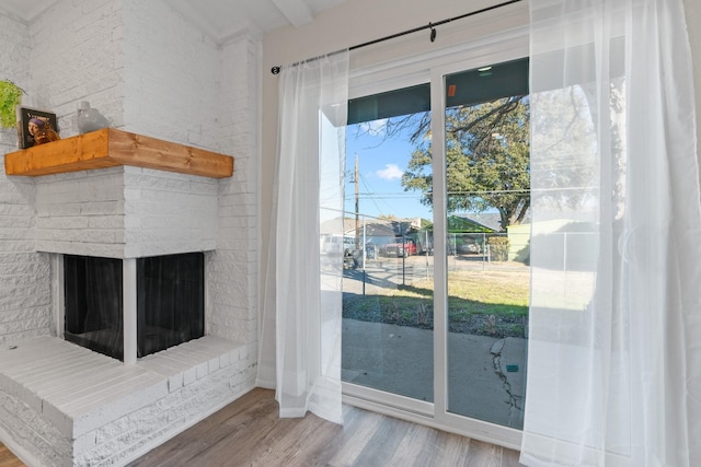 doorway with wood-type flooring and a brick fireplace