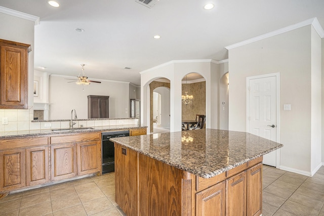 kitchen with black dishwasher, sink, backsplash, dark stone counters, and a center island