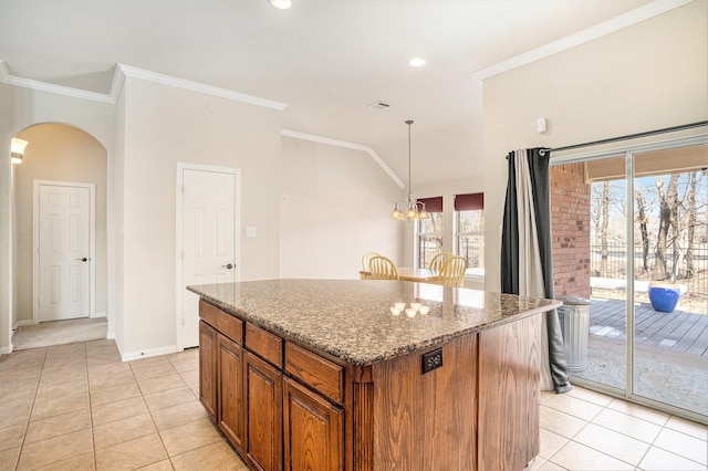 kitchen featuring hanging light fixtures, crown molding, dark stone counters, and a kitchen island