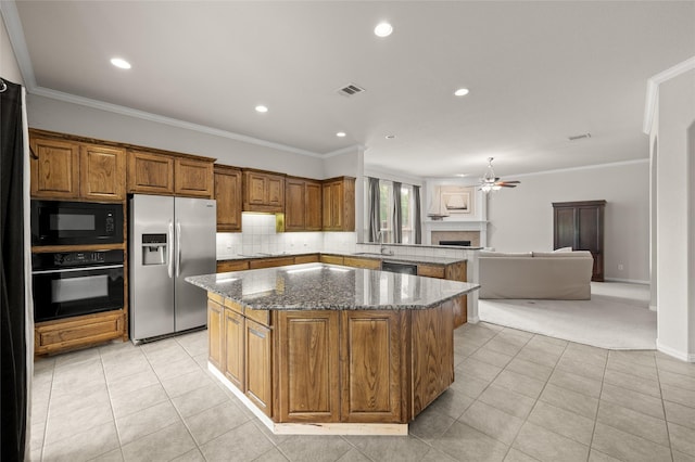 1417 Flying Jib Dr, Azle, TX 76020 - kitchen with black appliances, a center island, a tile fireplace, brown cabinets, and light tile patterned flooring