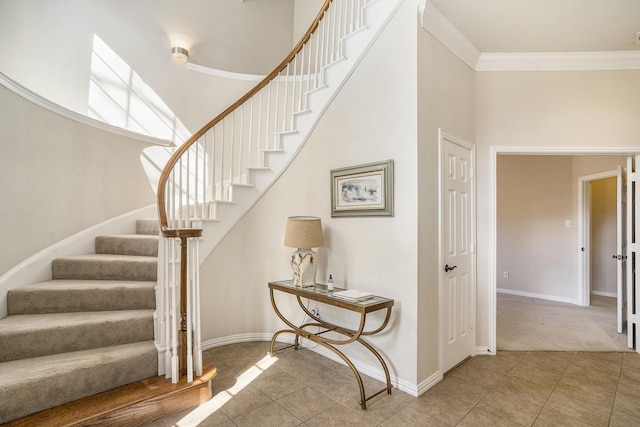 staircase featuring crown molding, a towering ceiling, and tile patterned floors