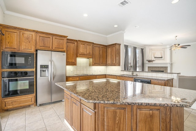 kitchen with sink, black appliances, a center island, stone counters, and backsplash