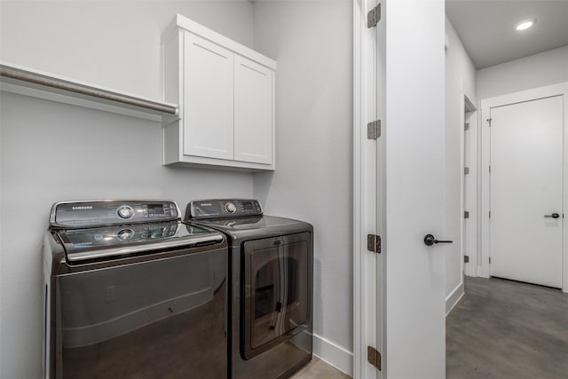 washroom with cabinets and washing machine and clothes dryer