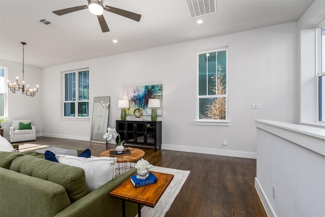 living room featuring dark wood-type flooring, plenty of natural light, and ceiling fan with notable chandelier