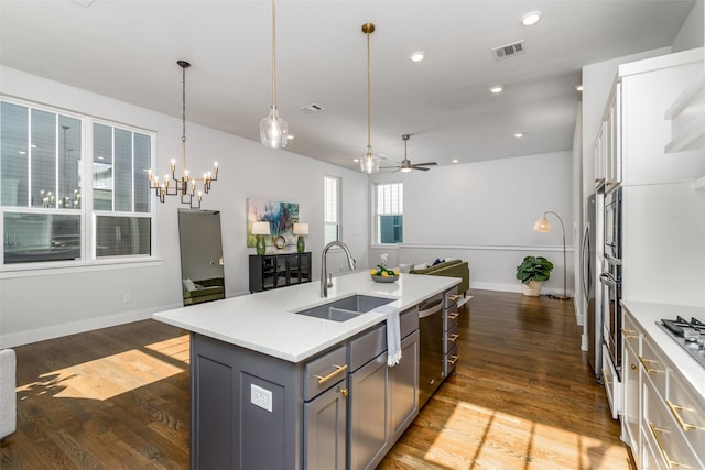 kitchen with pendant lighting, sink, appliances with stainless steel finishes, a kitchen island with sink, and gray cabinetry