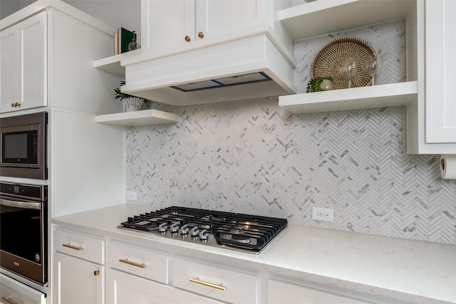 kitchen featuring premium range hood, tasteful backsplash, white cabinets, light stone counters, and stainless steel appliances