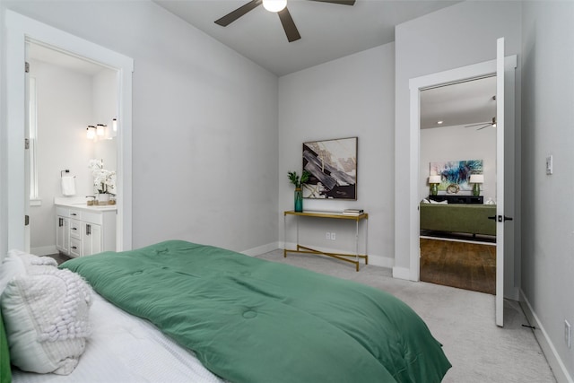 bedroom featuring connected bathroom, light colored carpet, and ceiling fan