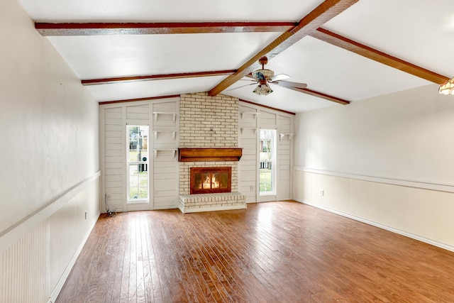 unfurnished living room with lofted ceiling with beams, ceiling fan, a fireplace, and hardwood / wood-style floors