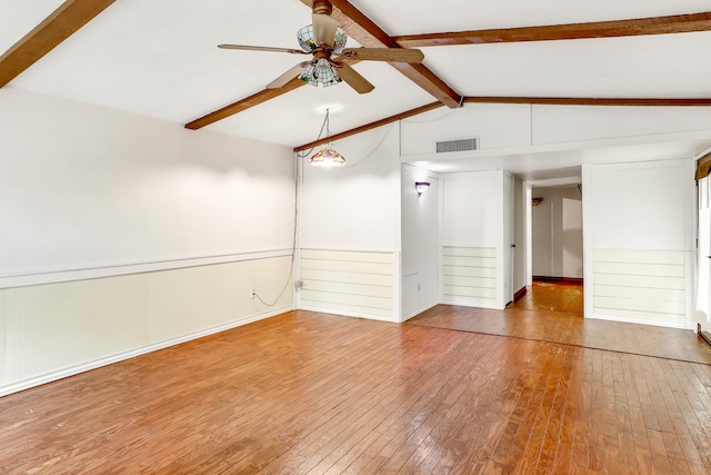 empty room featuring lofted ceiling with beams, ceiling fan, and hardwood / wood-style floors