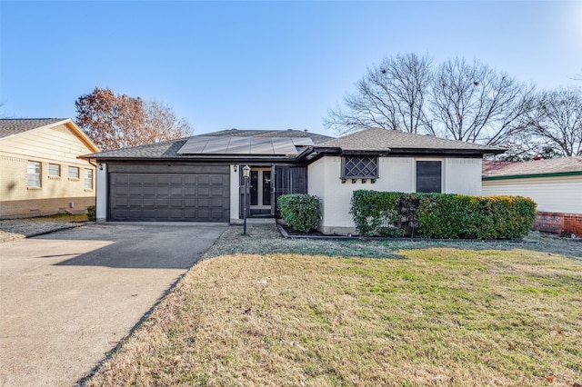 view of front of property featuring a garage, a front lawn, and solar panels