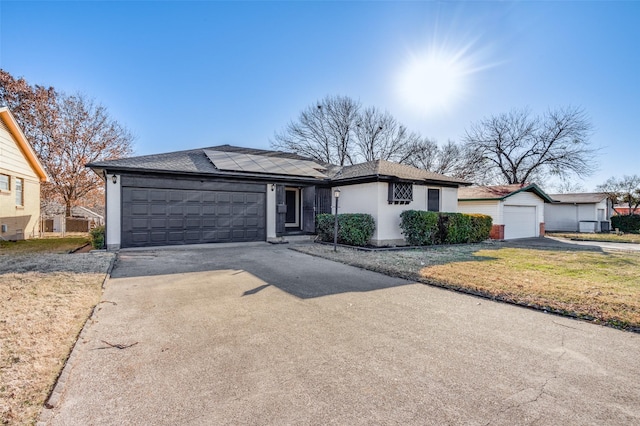 ranch-style house with a garage, a front yard, and solar panels