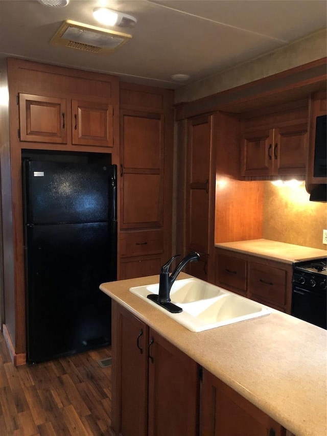 kitchen with sink, dark hardwood / wood-style floors, and black appliances