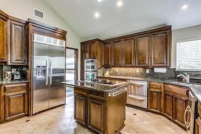 kitchen with vaulted ceiling, a kitchen island, appliances with stainless steel finishes, sink, and decorative backsplash