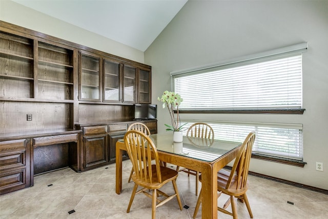 tiled dining space with vaulted ceiling, a healthy amount of sunlight, and built in desk