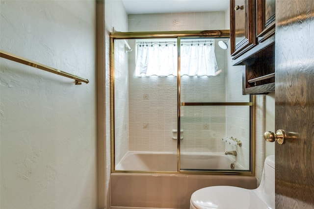 bathroom with toilet and shower / bath combination with glass door