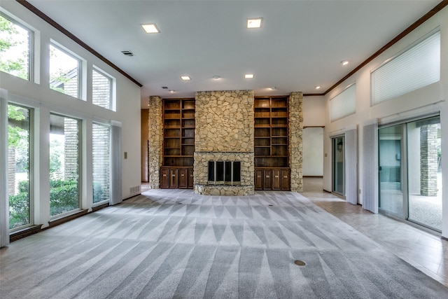 unfurnished living room with plenty of natural light, light carpet, a fireplace, and built in shelves