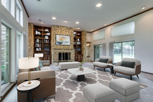 living room featuring built in shelves, a stone fireplace, a high ceiling, and a wealth of natural light