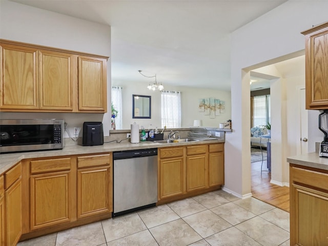 kitchen featuring stainless steel appliances, sink, light tile patterned floors, and a chandelier