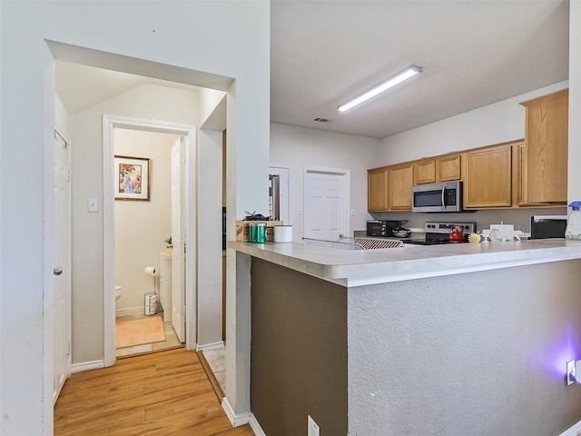 kitchen featuring stainless steel appliances, light hardwood / wood-style floors, and kitchen peninsula