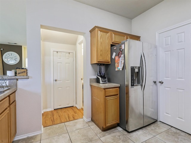 kitchen with stainless steel refrigerator with ice dispenser and light tile patterned flooring