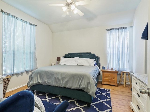 bedroom featuring multiple windows, lofted ceiling, ceiling fan, and light hardwood / wood-style flooring