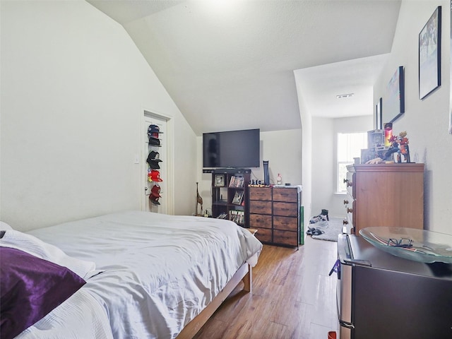 bedroom with lofted ceiling and light wood-type flooring