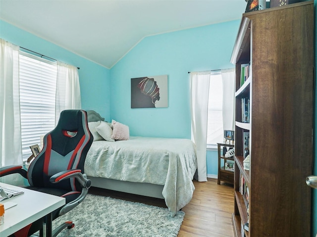 bedroom featuring light hardwood / wood-style flooring, multiple windows, and vaulted ceiling